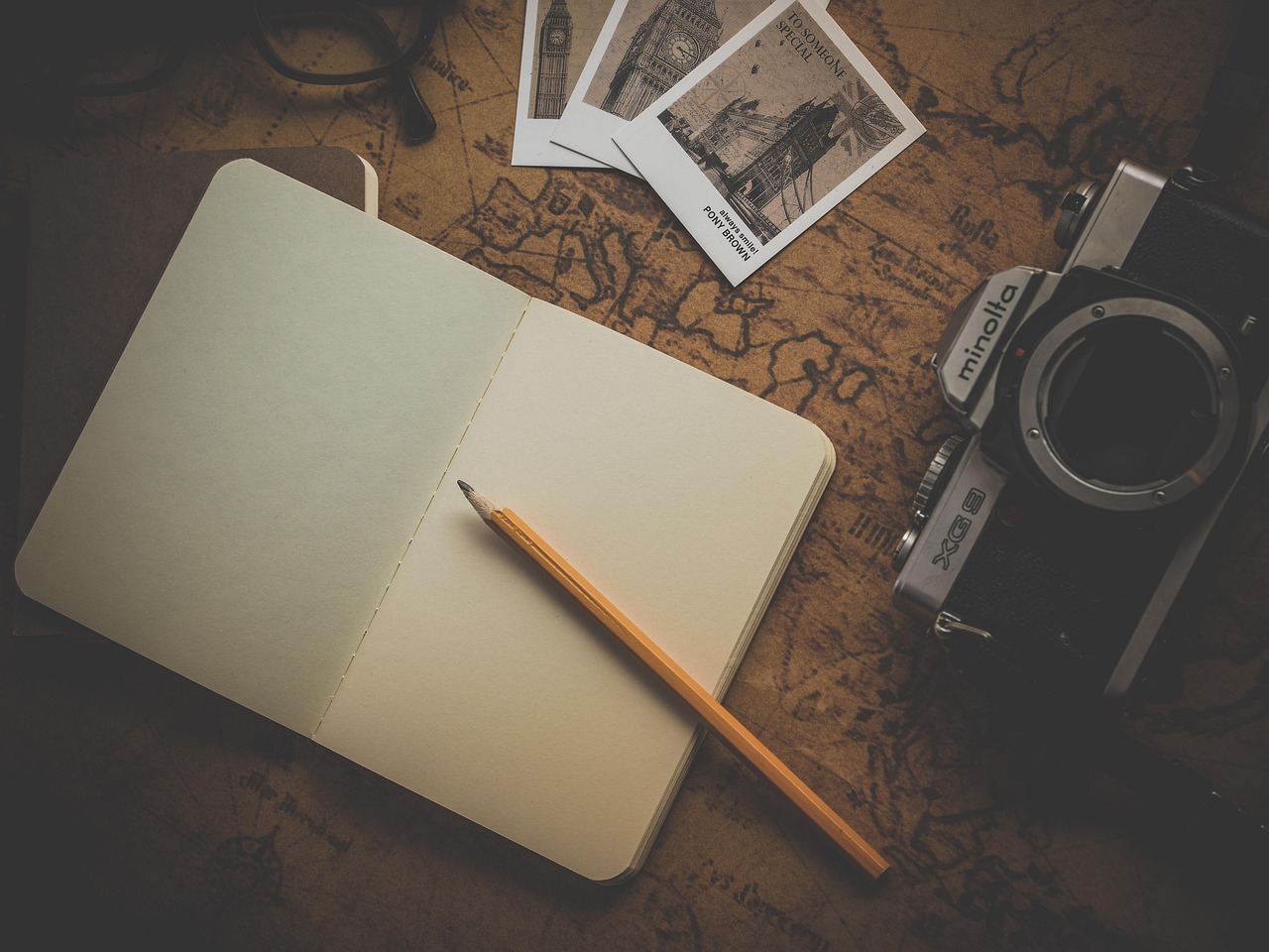 Open travel journal notebook on a wooden table with a pen resting on the page