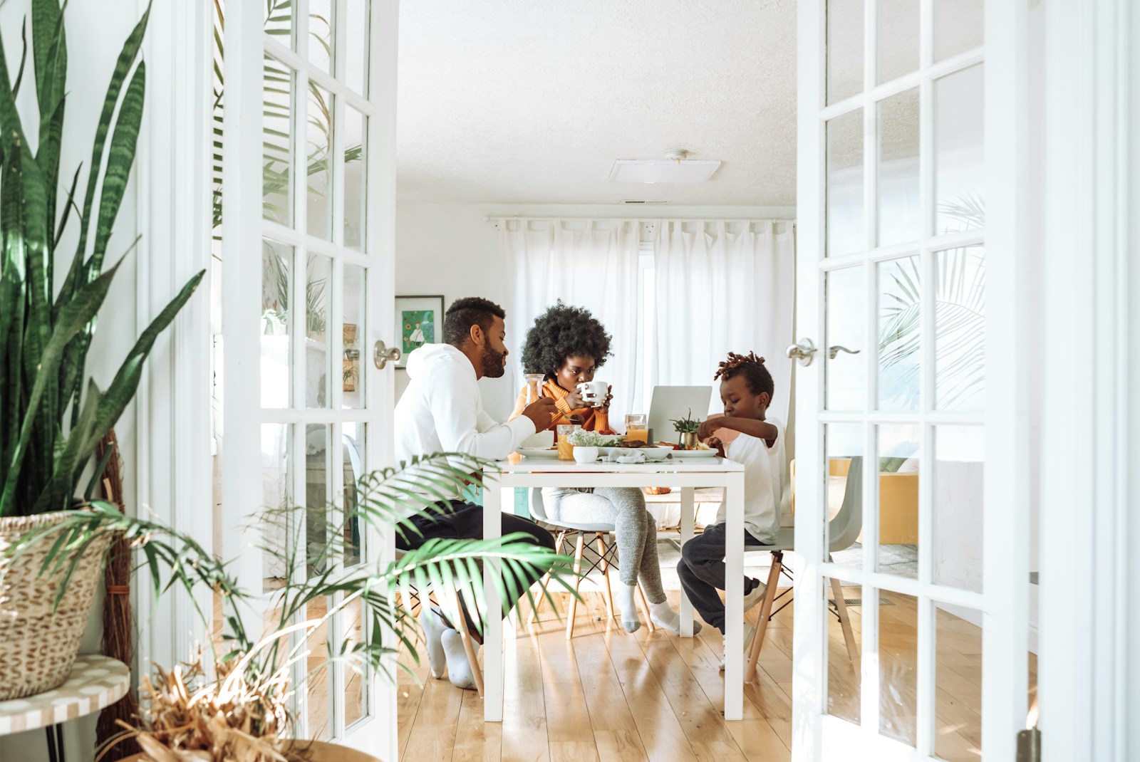 A family of four eating a simple breakfast of cereal and fruit in a hotel room with a small kitchenette