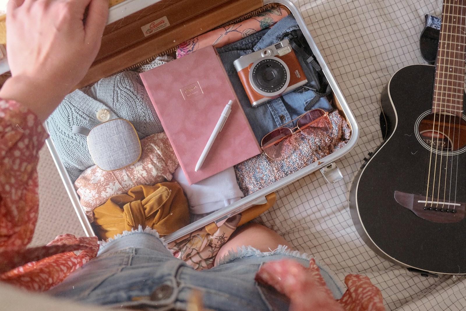 A travel scarf and sarong laid out with sunscreen and a power bank for a Bali trip