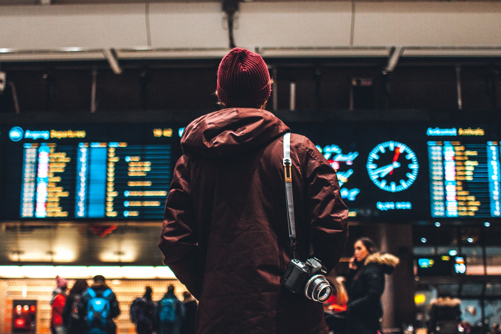 A traveler with luggage checking a train schedule on a smartphone in a train station