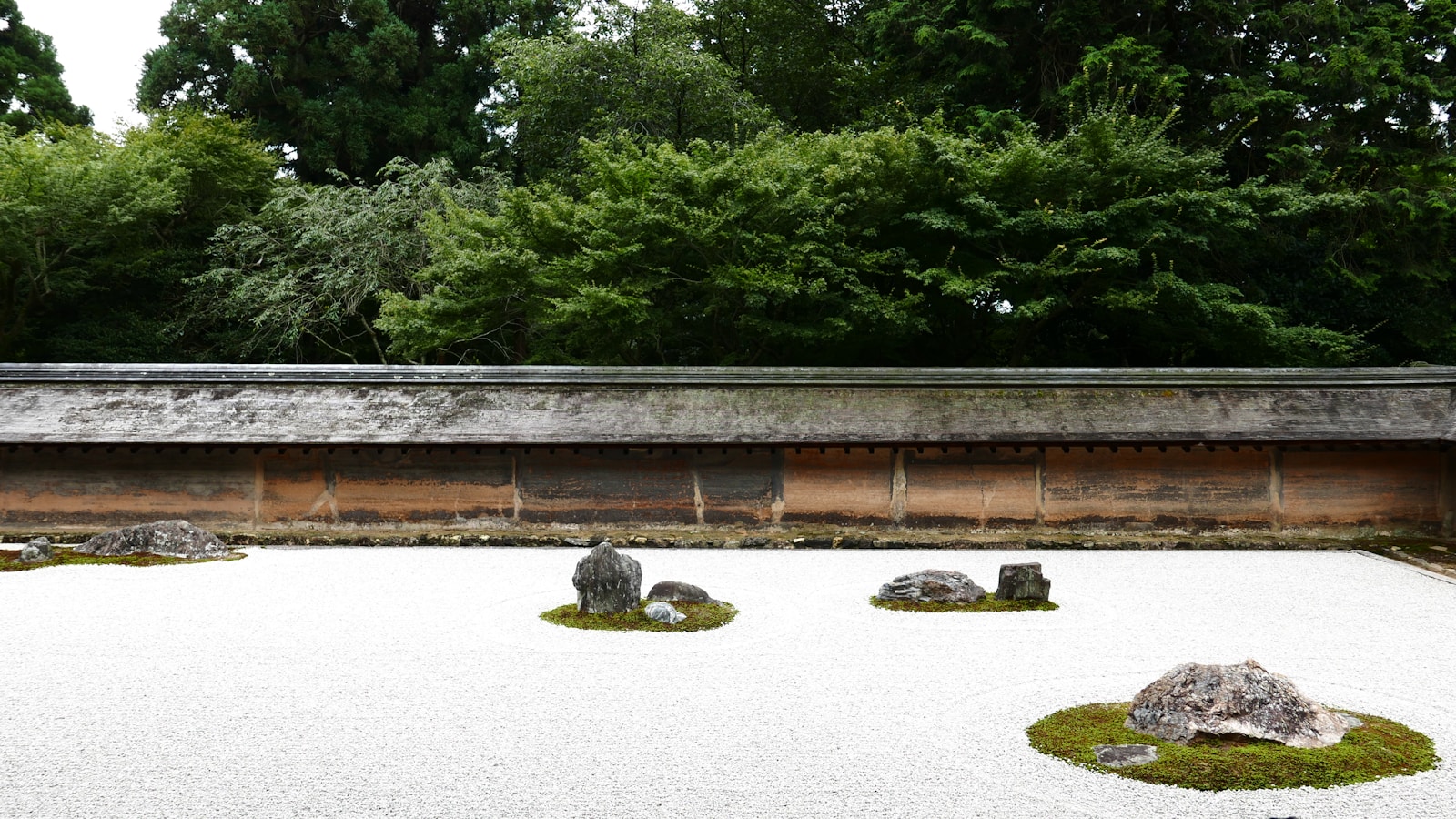 The famous Zen rock garden at Ryoan-ji temple in Kyoto with carefully raked gravel and moss-covered stones