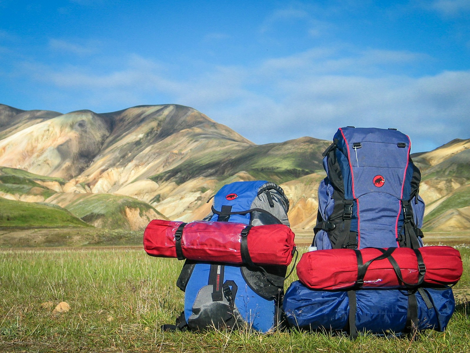 Backpacker organizing travel essentials like a backpack, power bank, and water bottle on a hostel bed