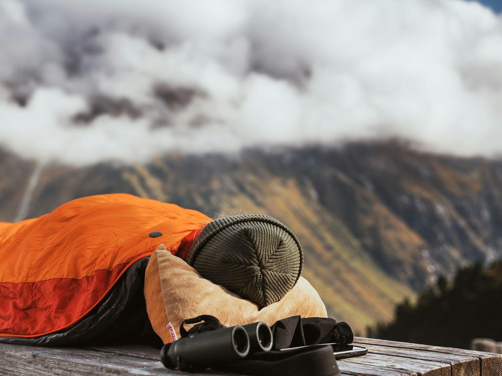 Travel sleep mask, noise-canceling earbuds, and a combination lock placed neatly on a hostel pod bed
