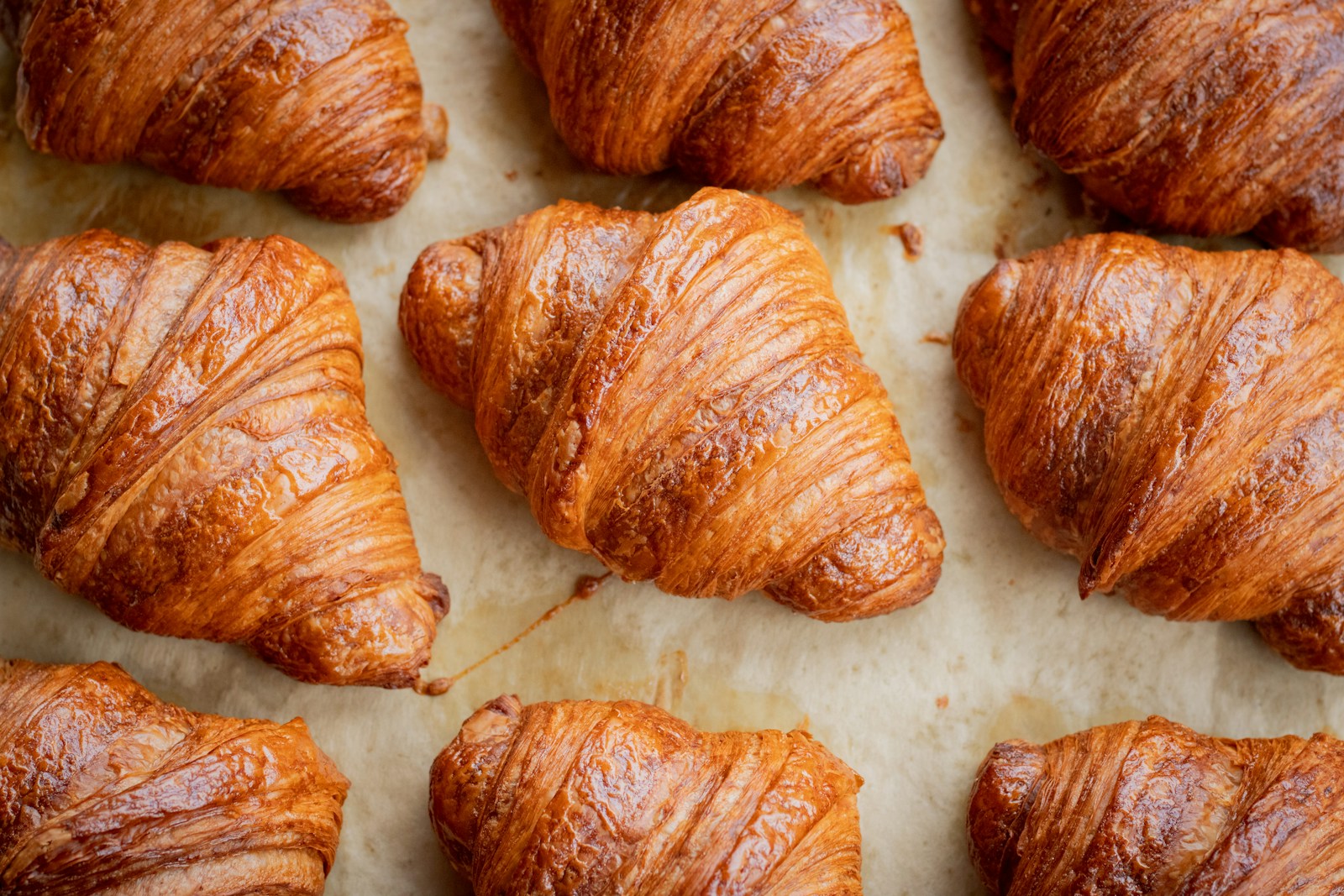 A golden croissant and a baguette on a wooden board