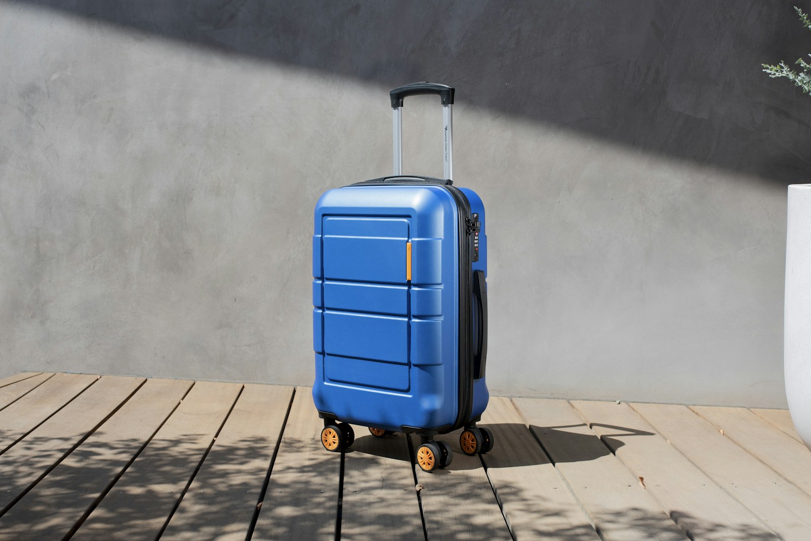 A black hard-shell carry-on suitcase placed inside an airplane overhead bin