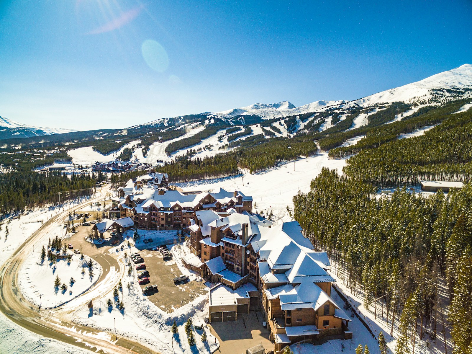 Aerial view of a luxury ski resort with snowy slopes and alpine peaks in winter