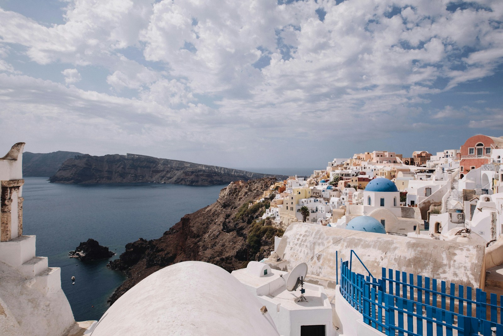 Iconic white-washed buildings with blue domes in Santorini overlooking the caldera and the deep blue Aegean Sea