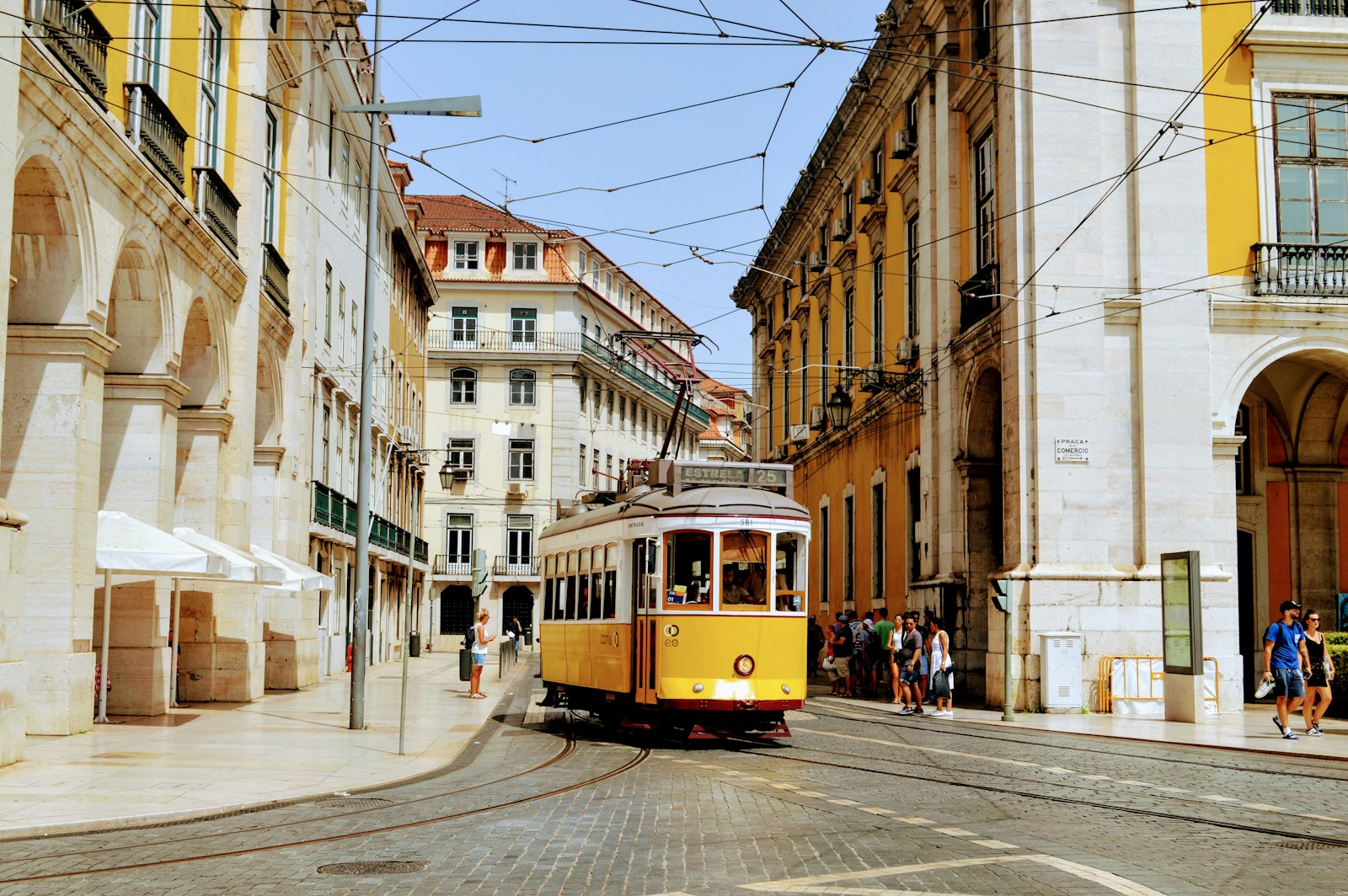Yellow Tram 28 passing through narrow Lisbon streets with cobblestones