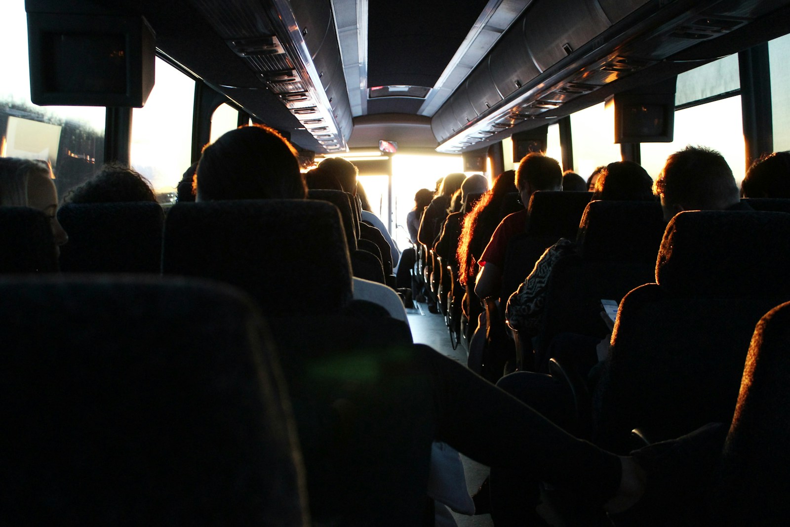 Person sleeping on an overnight bus using a travel pillow and eye mask