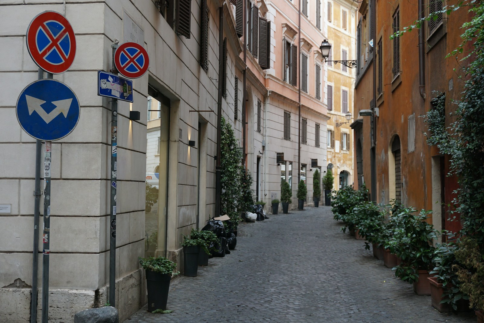 A narrow cobblestone street in Trastevere, Rome, in the evening with string lights