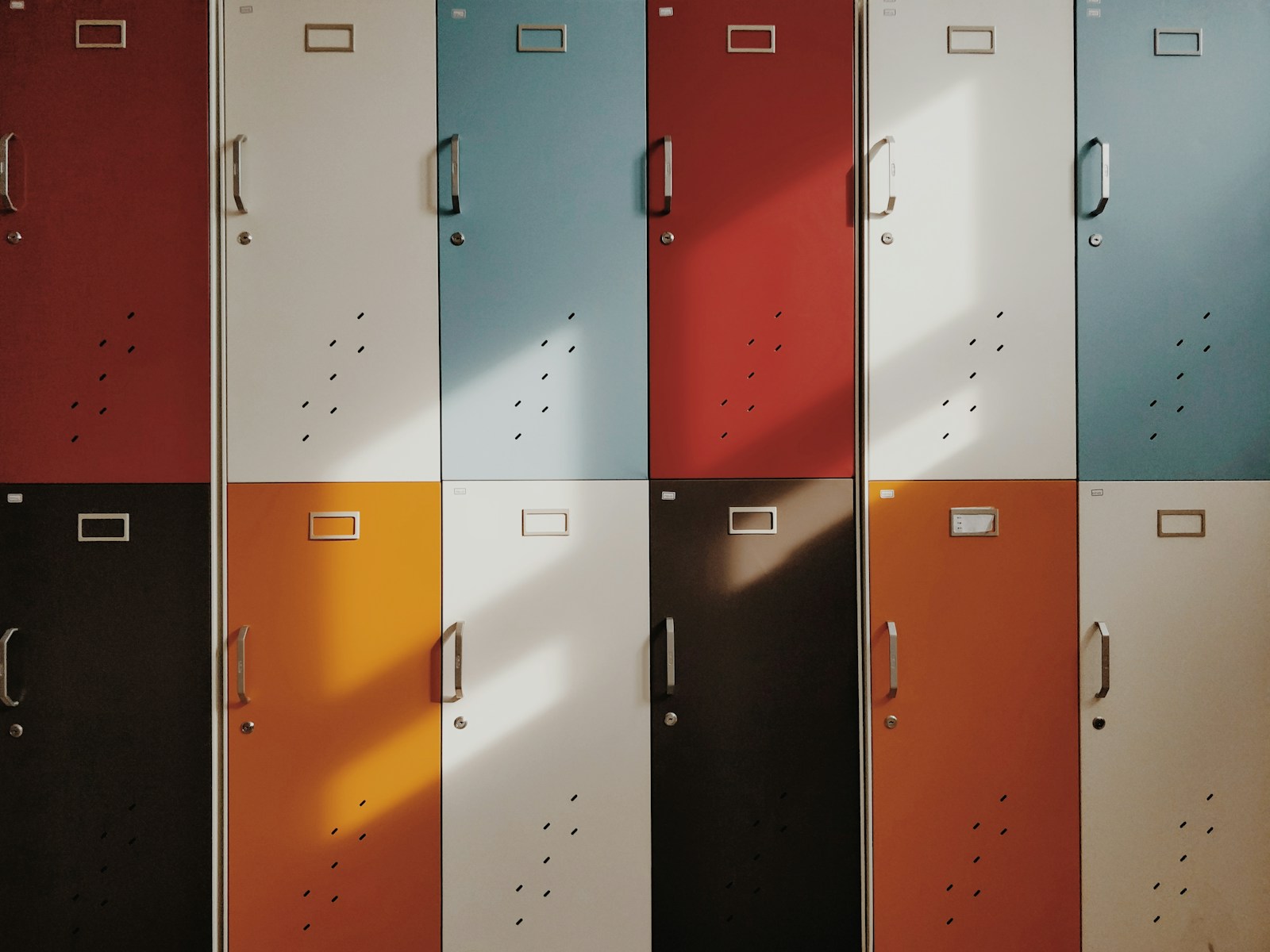 Large under-bed locker inside a hostel dorm with a 50-liter backpack placed inside and a combination lock on the latch