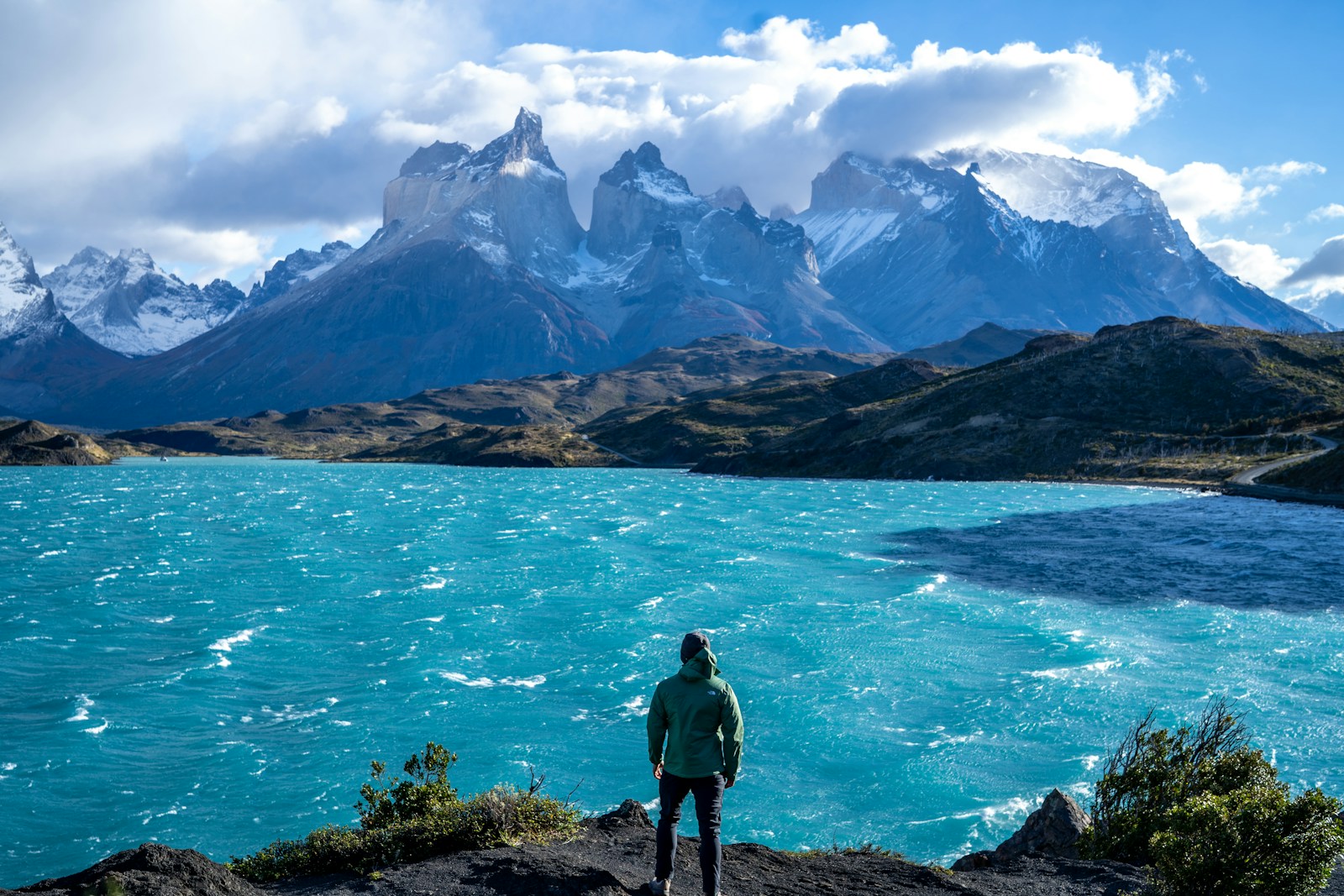 Hiker on a trail in Torres del Paine National Park with towering granite peaks in the background
