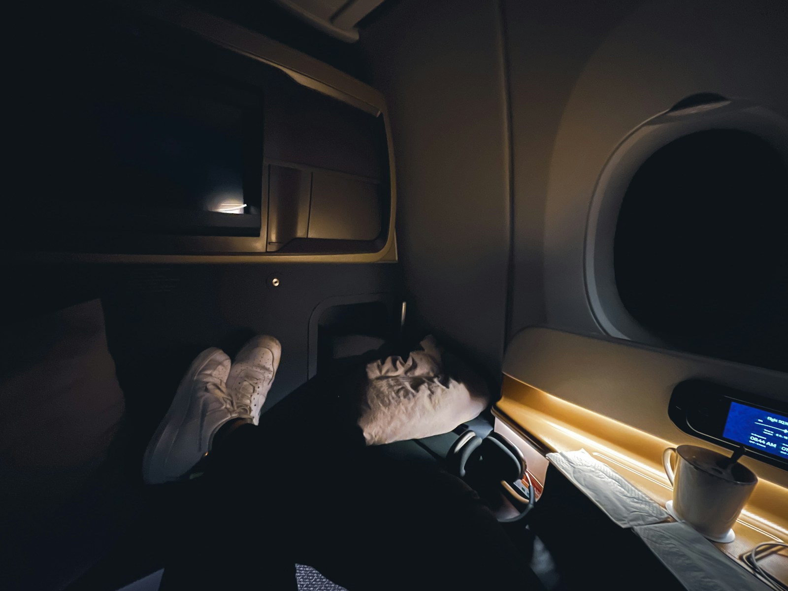 A business traveler sleeping comfortably on a long flight using a neck pillow and sleep mask